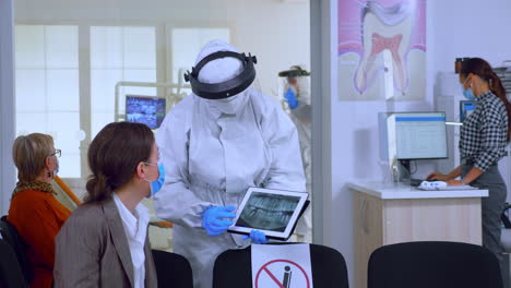 Stomatologist-in-protective-suit-pointing-on-digital-x-ray
