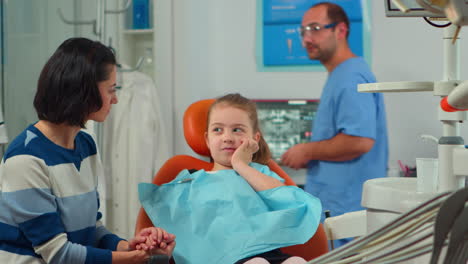 Mother-and-daughter-with-dental-bib-waiting-in-clinic-room-for-pediatric-dentist