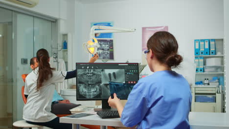 Stomatologist-nurse-comparing-radiographics-looking-at-computer