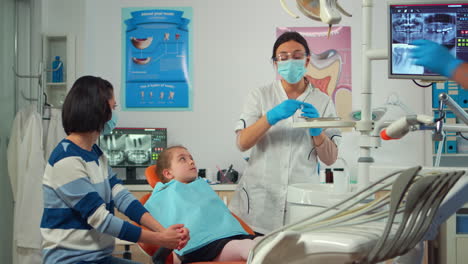 Dentista-Pediátrico-Con-Máscara-Comprobando-La-Salud-Dental-De-Una-Niña