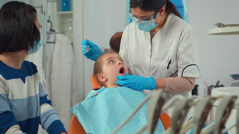 Kinderzahnarzt-Mit-Maske-Behandelt-Die-Zähne-Einer-Kleinen-Patientin