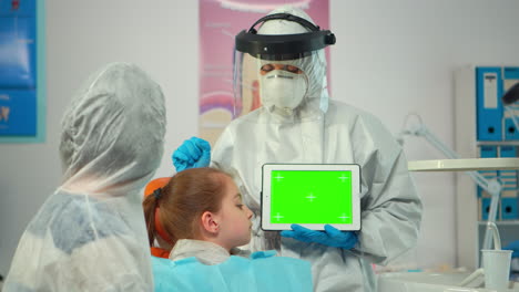 Stomatologist-with-coverall-pointing-at-mockup-greenscreen-display