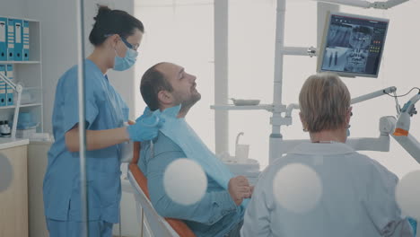 Dentist-showing-teeth-radiography-to-patient-on-dental-chair