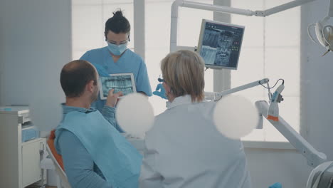Equipo-De-Odontología-Mostrando-Rayos-X-De-Dientes-A-Un-Paciente-Con-Dolor-De-Muelas