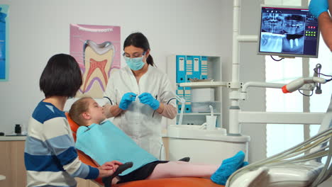 Enfermera-Pediátrica-Y-Dentista-Que-Trabaja-En-Una-Clínica-Dental-Moderna-Que-Trata-A-Una-Niña