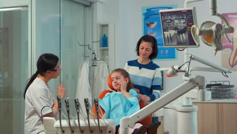 Pediatric-woman-dentist-talking-with-mother-and-girl-about-oral-hygiene