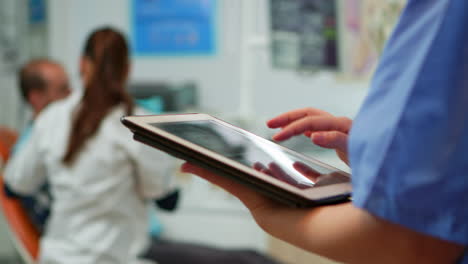 Close-up-of-nurse-holding-and-typing-on-tablet