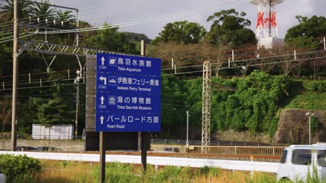 Cars-Passing-Road-Sign-in-Toba-City,-Mie-Prefecture-Japan