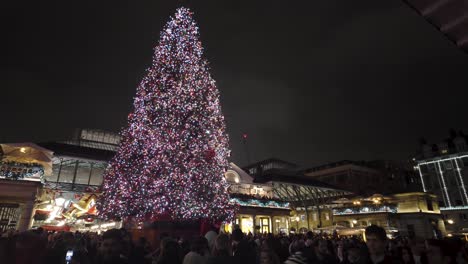Beleuchteter-Festlicher-Weihnachtsbaum-Im-Covent-Garden-Mit-Geschäftigen-Menschenmassen,-Die-Nachts-Vorbeigehen