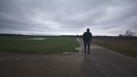 Modern-Black-Male-Waiting-in-Open-Field-Under-Grey-Sky,-Europe,-4K-|-Muscular,-Intimidating,-Shadow,-Figure,-Blurry,-Dark-Clothes,-Powerful,-Walk-Towards,-Distant,-Thought,-Thinking