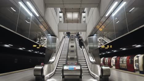 Doppelte-Rolltreppen-In-Der-U-Bahn-Des-Battersea-Kraftwerks-Mit-Ankommendem-Zug-Auf-Der-Linken-Seite