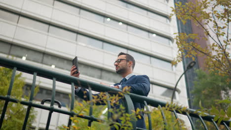 Businessman-uses-phone-outdoors
