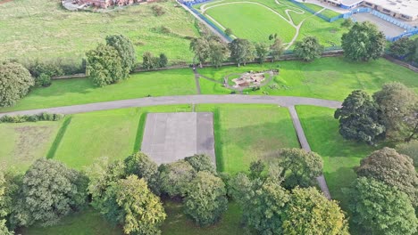 Sinking-aerial-of-football-pitch-and-green-fields-in-Bradford,-UK