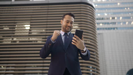 Amazed-happy-businessman-receiving-sms-message-reading-good-news