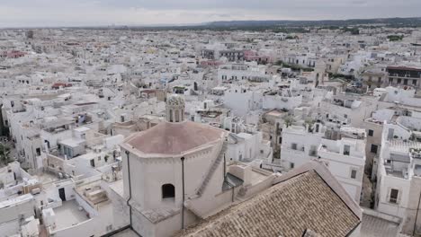 Aerial-footage-in-the-town-of-Polignano-a-Mare-flying-towards-a-mosaic-dome-of-a-church