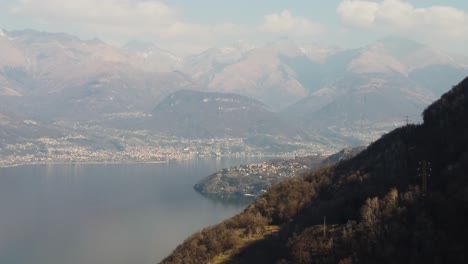 Township-on-lake-Como-coast-with-mountains-in-background,-aerial-view