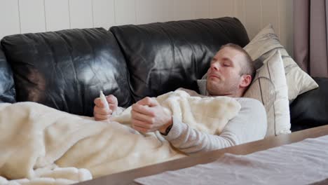 Sick-Man-Under-Blanket-Uses-Nasal-Spray-for-Relief