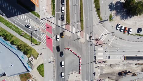 Cars-driving-on-intersection-in-busy-city,-aerial-top-down-view