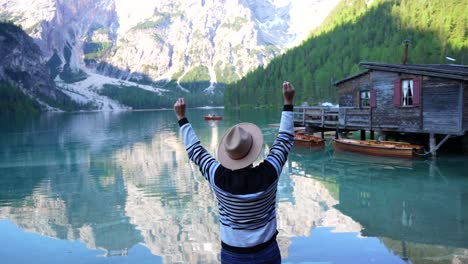 Rear-shot-of-man-with-hat-celebrating-near-scenic-Lago-di-Braies