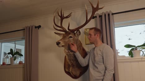 Proud-man-checking-his-massive-deer-buck-trophy-in-the-living-room