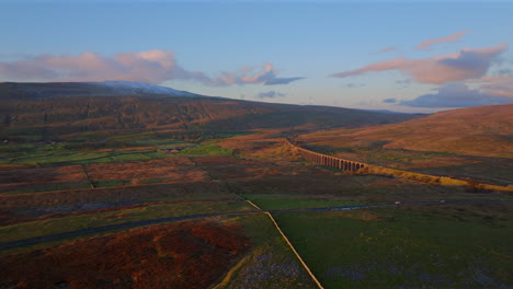 Establishing-Aerial-Drone-Shot-of-Riblehead-Viaduct-and-Whernside-Snowy-Mountain-at-Golden-Hour-Sunset-in-Yorkshire-Dales-UK