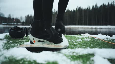 Strapping-on-wakeboard-bindings-in-snowy-environment