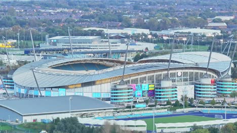 Aerial-pan-of-Etihad-Stadium,-home-soccer-arena-of-Manchester-City,-UK