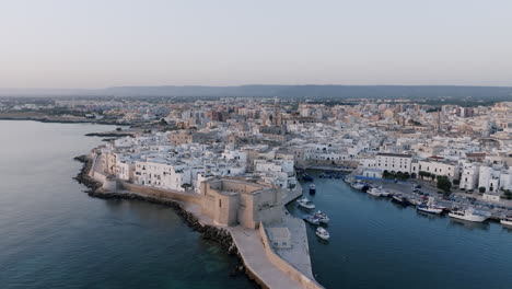 Aerial-footage-of-the-town-of-Monopoli,-Italy-in-the-morning-light-and-the-boat-harbor-in-the-Mediterranean-Sea