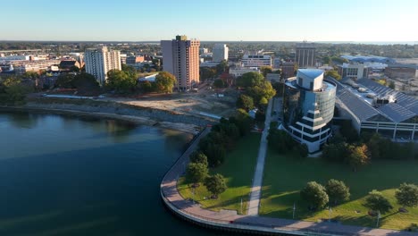 Downtown-Newport-News,-Virginia-skyline-on-bright-autumn-day-as-seen-from-drone-above-James-River
