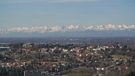 Small-township-of-Lombardia-and-snowy-mountains-in-horizon,-static-view