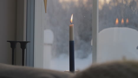 Candle-symbol-of-Finlands-independence-lit,-wind-blows-snow-outdoors-in-background