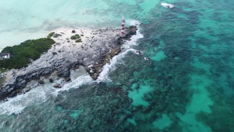 Aerial-view-of-Caribbean-Sea-waves-breaking-on-rocky-coast-of-Vintage-Lighthouse-in-Punta-Cancun,-Mexico