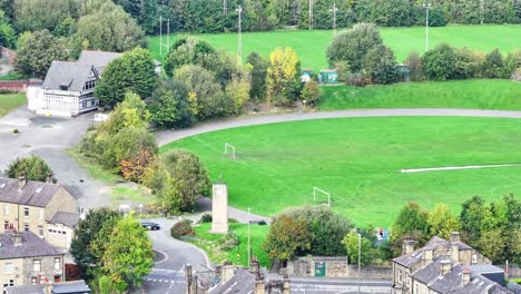Aerial-of-football-and-rugby-fields-by-buildings-in-Huddersfield,-UK