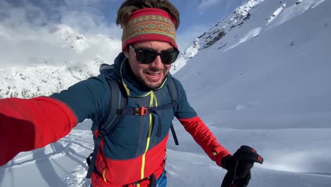 Young-athlete-ski-touring-a-high-snowy-mountain-while-filming-himself