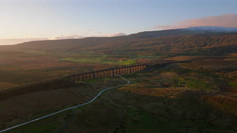 Absteigende-Drohnenaufnahme-Des-Ribblehead-Viadukts-Und-Des-Schneebedeckten-Whernside-Mountain-Bei-Sonnenuntergang-In-Yorkshire-Dales,-Großbritannien