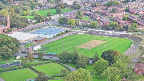 Rising-aerial-of-cricket-ground,-parks-and-buildings-in-Bradford,-UK