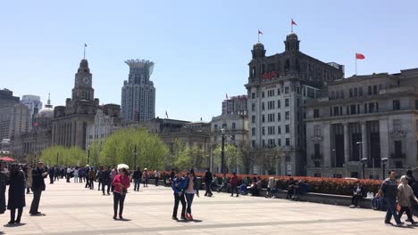 People-and-tourists-walking-in-front-of-AIA-Shanghai-Office-and-Custom-House-Building-at-Bund,-Shanghai,-China