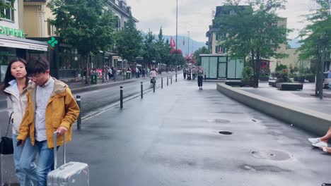 Interlaken-Switzerland-Immersive-Travel-Tourism-Mountainside-Valley-Resort-City,-Europe,-Walking,-Rainy-Day,-4K-|-Looking-Around,-Shaky,-Water,-River,-Lake,-Restaurant,-Couple,-Bikes,-Busy,-Hiker