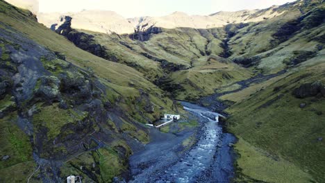 Thermal-bath-Seljavallalaug,-scenic-volcanic-Icelandic-nature,-aerial-dolly-out