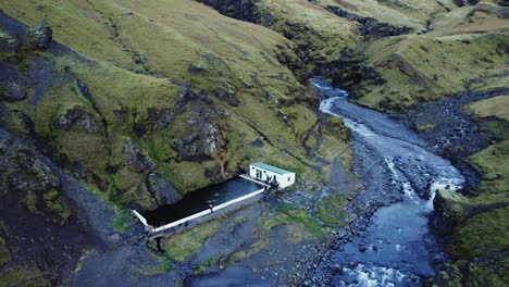 Famous-public-outdoor-swimming-pool-Seljavallalaug,-Iceland,-aerial-establisher