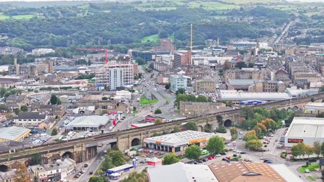 Train-tracks,-town-centre-and-and-forest-in-Huddersfield,-UK,-aerial