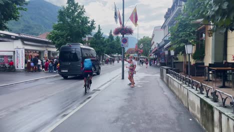 Interlaken-Switzerland-Immersive-Travel-Tourism-Mountainside-Valley-Resort-City,-Europe,-Walking,-Rainy-Day,-4K-|-Looking-Around,-Shaky,-Water,-River,-Lake,-Restaurant,-Biker,-Street-Crossing,-Couple