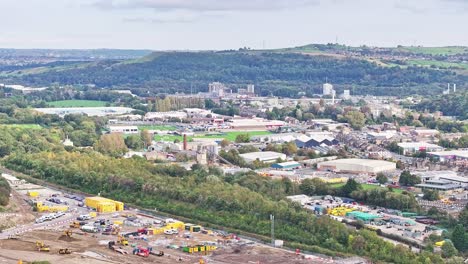 Wide-sinking-aerial-of-industrial-area-and-forest-in-Huddersfield,-UK