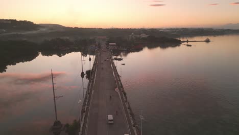 Golden-hour-aerial-view-of-Dauis-bridge-traffic-and-sky-reflection-on-water