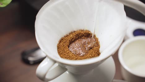 Barista-Gießt-Heißes-Wasser-Aus-Dem-Wasserkocher-Mit-Schwanenhals-über-Gemahlene-Kaffeebohnen