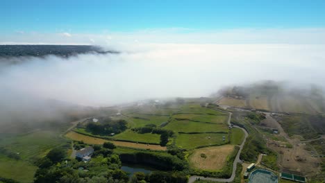 The-fog-coming-in-off-the-sea-over-fields-in-Guernsey-on-otherwise-bright-sunny-day-aerial-footage