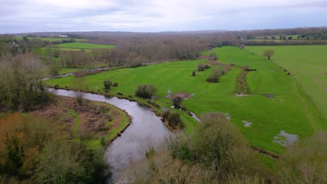 Flight-over-river-and-small-bridge-in-lush-green-Southdowns-countryside-in-winter-no-leaves-on-trees