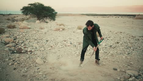 Israeli-man-use-spade-to-bury-items-in-hole-in-dry-desert-soil,-shovelling-dirt