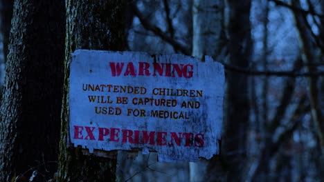 Dark-eerie-distressed-sign-warning-of-experimental-medical-procedures-on-children-in-remote-woodland-forest