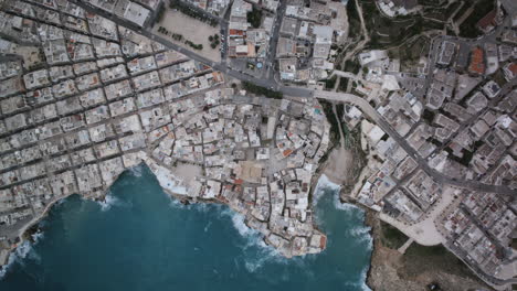 Top-down-aerial-timelapse-of-the-town-of-Polignano-a-Mare-with-the-water-of-the-sea-crashing-up-against-the-coast